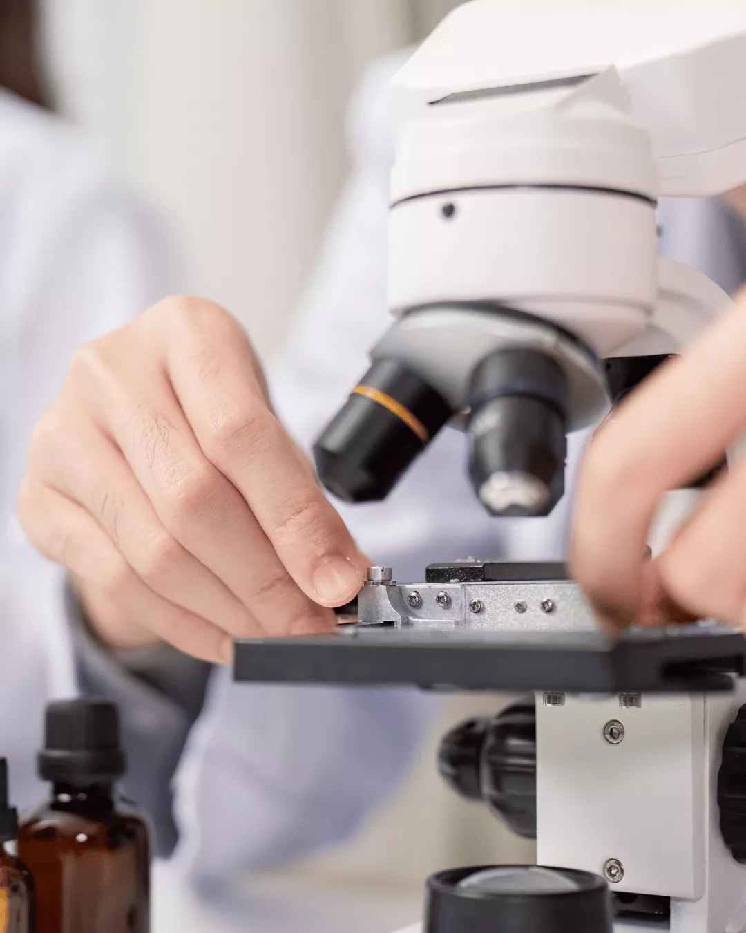 A scientists performs a microbial analysis using a microscope in a laboratory setting.