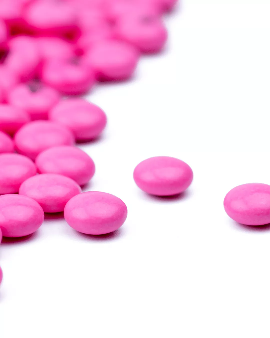 Pink sugar coated tablets against a white background.