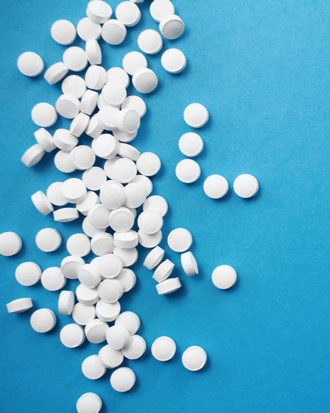White round tablets splayed against a blue background.