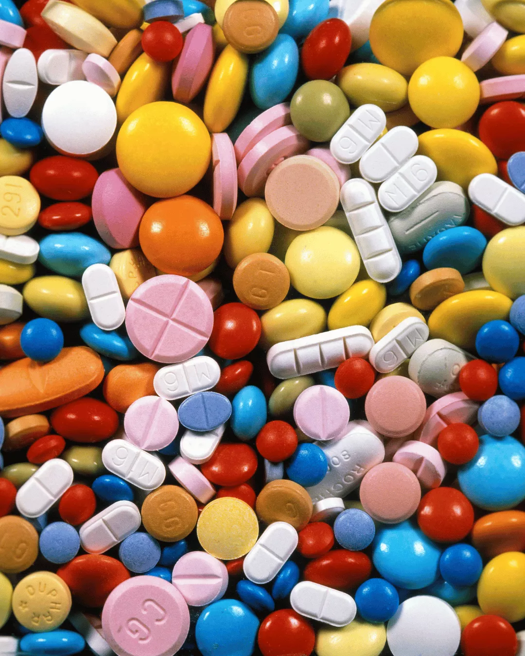 A pile of coated tablets in a variety of shapes and colors.