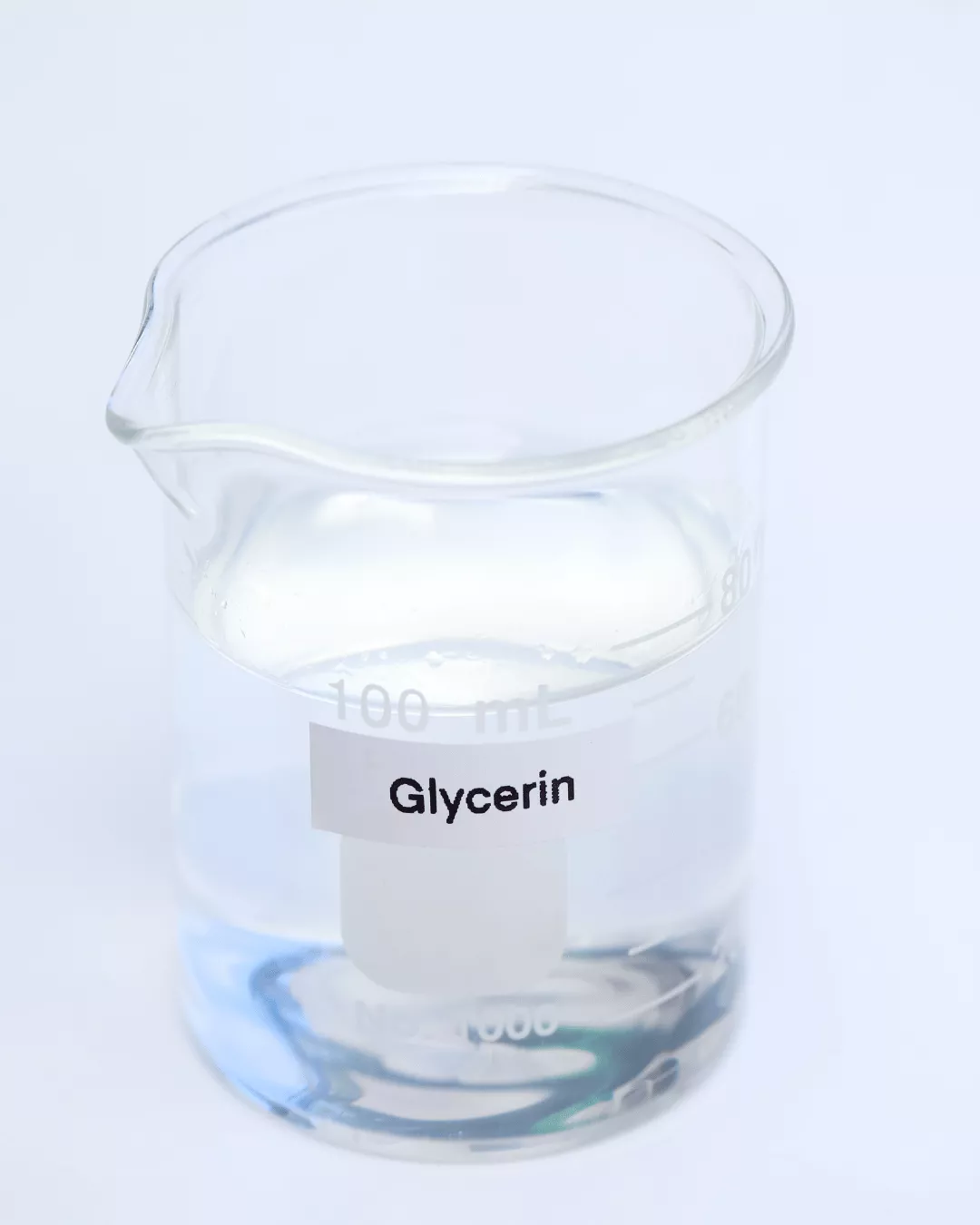 A glass container with a printed label that says Glycerin. It contains clear liquid (glycerin).