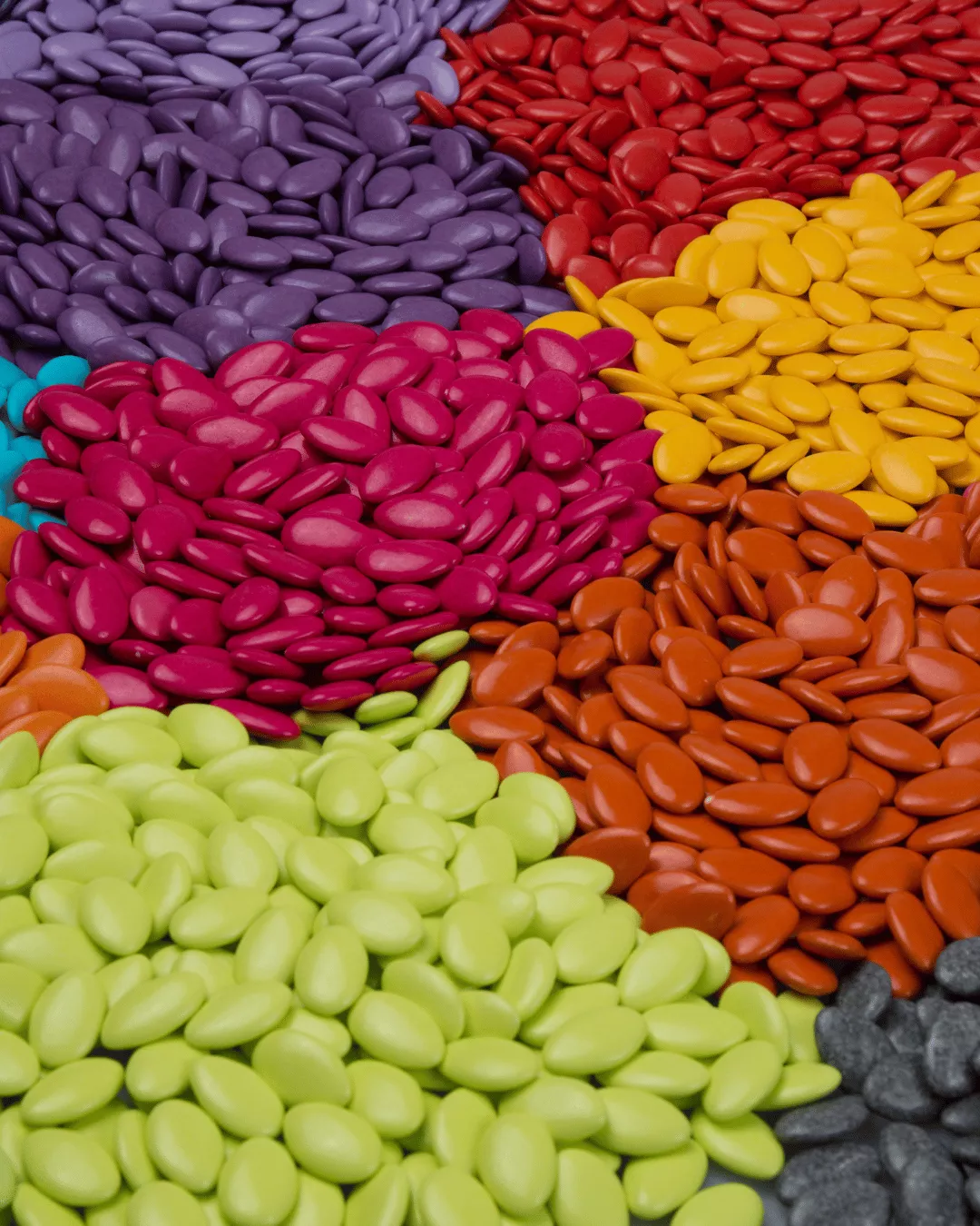 Piles of red, green, yellow, and pink sugar coated tablets.