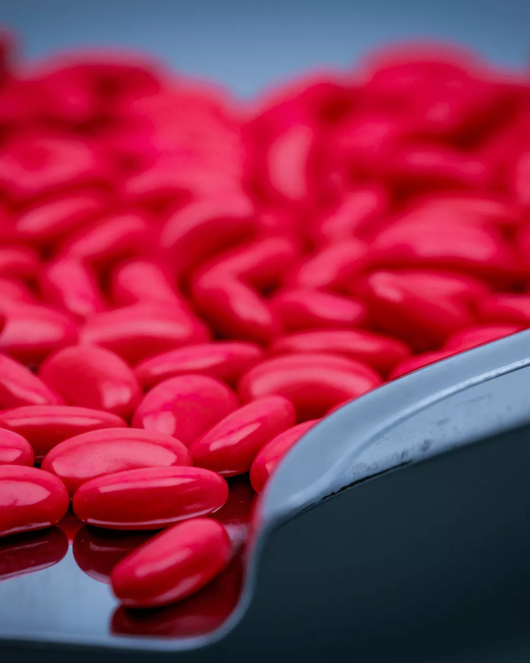 Glossy, red sugar coated tablets in a tablet counting machine.