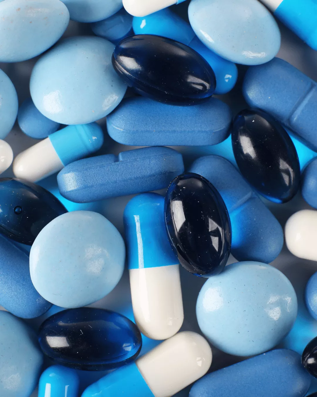 Coated blue tablets alongside blue capsules.