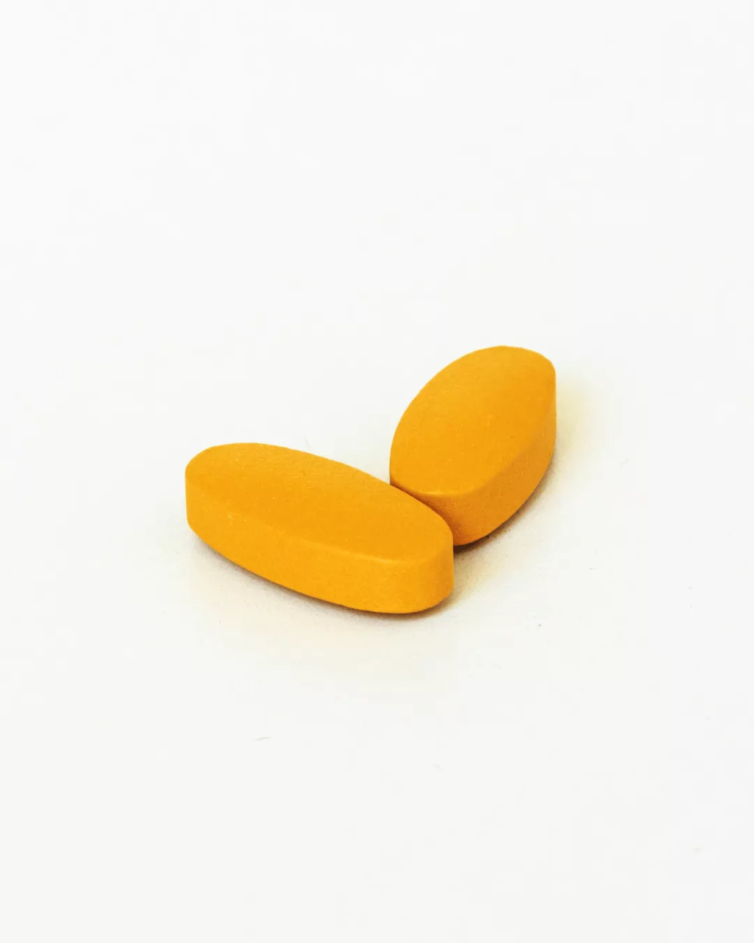 Two yellow coated tablets against a white background.