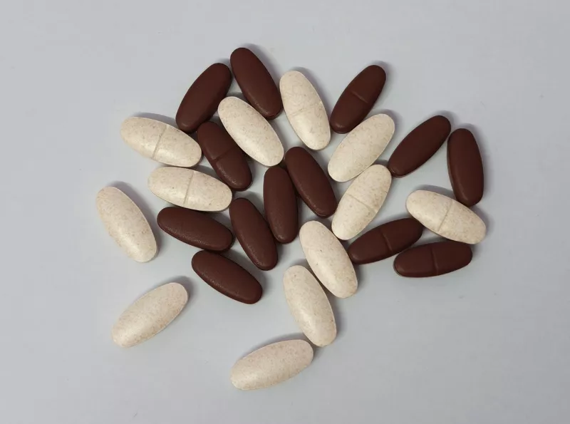 Brown and tan oval bisected tablets against a gray background.